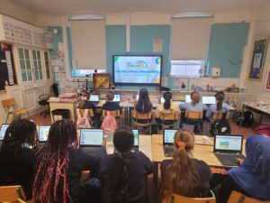 Primary school pupils participating in a whole-class coding lesson using laptops