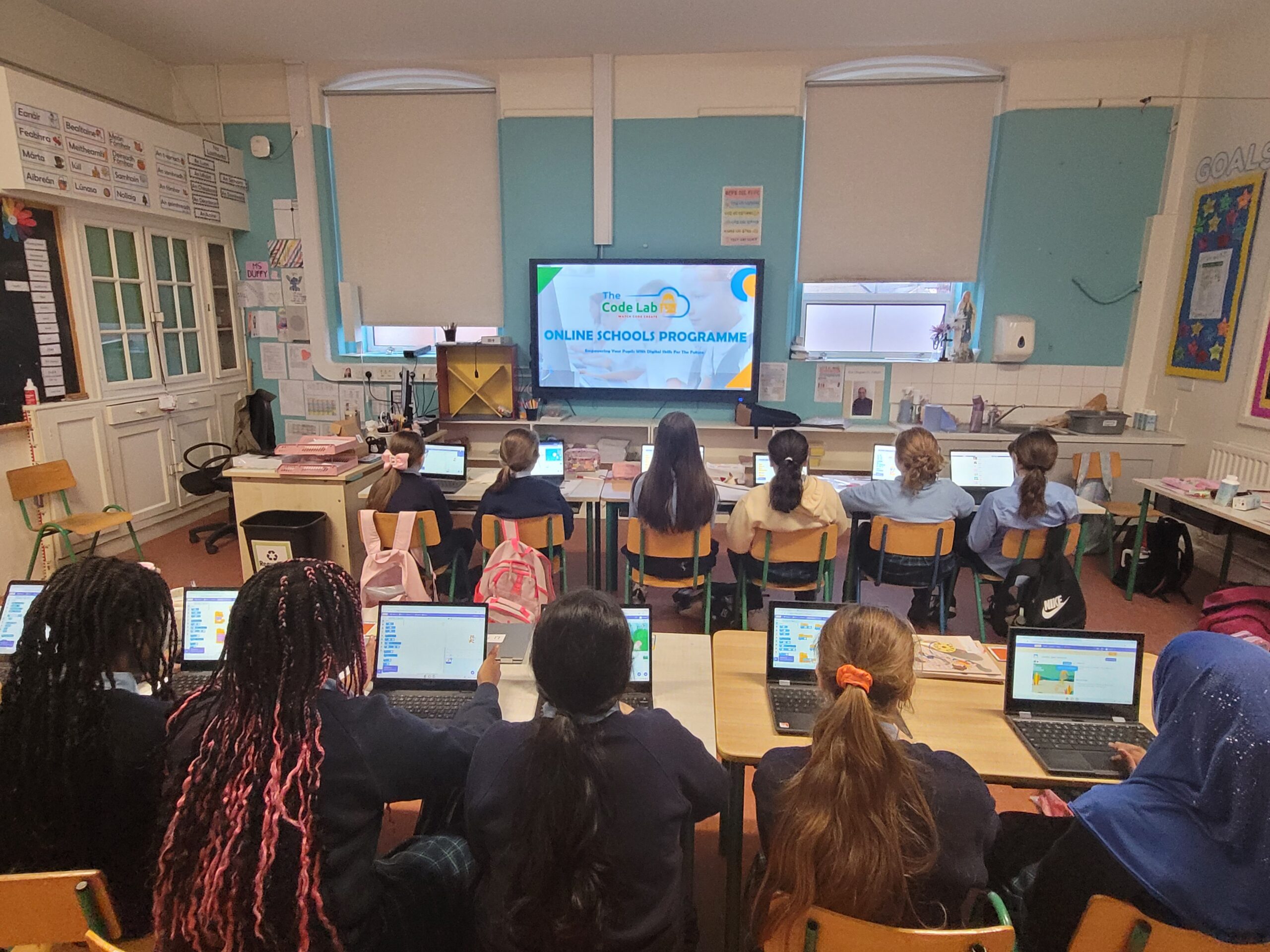 Primary school pupils participating in a whole-class coding lesson using laptops